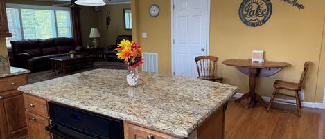 A kitchen with granite countertops, a built-in oven, wooden cabinets, and a central island with a vase of flowers.