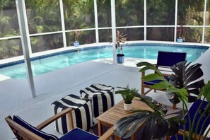 A poolside area with a clear view of the pool, lounge chairs, and potted plants. - Charming Private Pool Home Close to Beach Golf Cart (St. Petersburg)