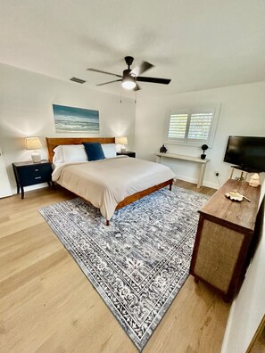 A bedroom with a bed, nightstands, a ceiling fan, a TV, and a window with blinds. - Charming Private Pool Home Close to Beach Golf Cart (St. Petersburg)