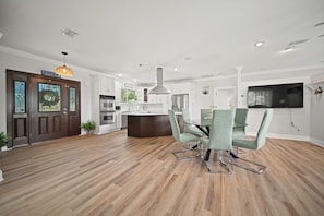 A modern kitchen with a central island, stainless steel appliances, and a dining area with green upholstered chairs. - About a 9 min walk to St. Augustine Beach, with easy day trips up the coast (St. Augustine)