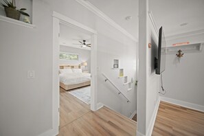 Ein modernes Schlafzimmer mit einem Bett, einem Nachttisch, einem Deckenventilator und einem Fenster.