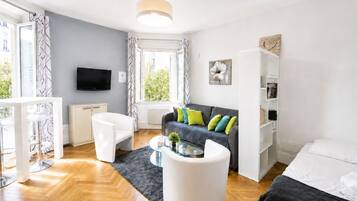 Un salon moderne avec un canapé, des fauteuils, une table basse et un téléviseur.