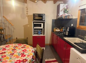 A compact kitchen with a microwave, oven, and sink. - Maison en ossature bois à Vensac Océan (Vensac)
