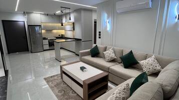 A modern living room with a sofa, coffee table, and a kitchen in the background.