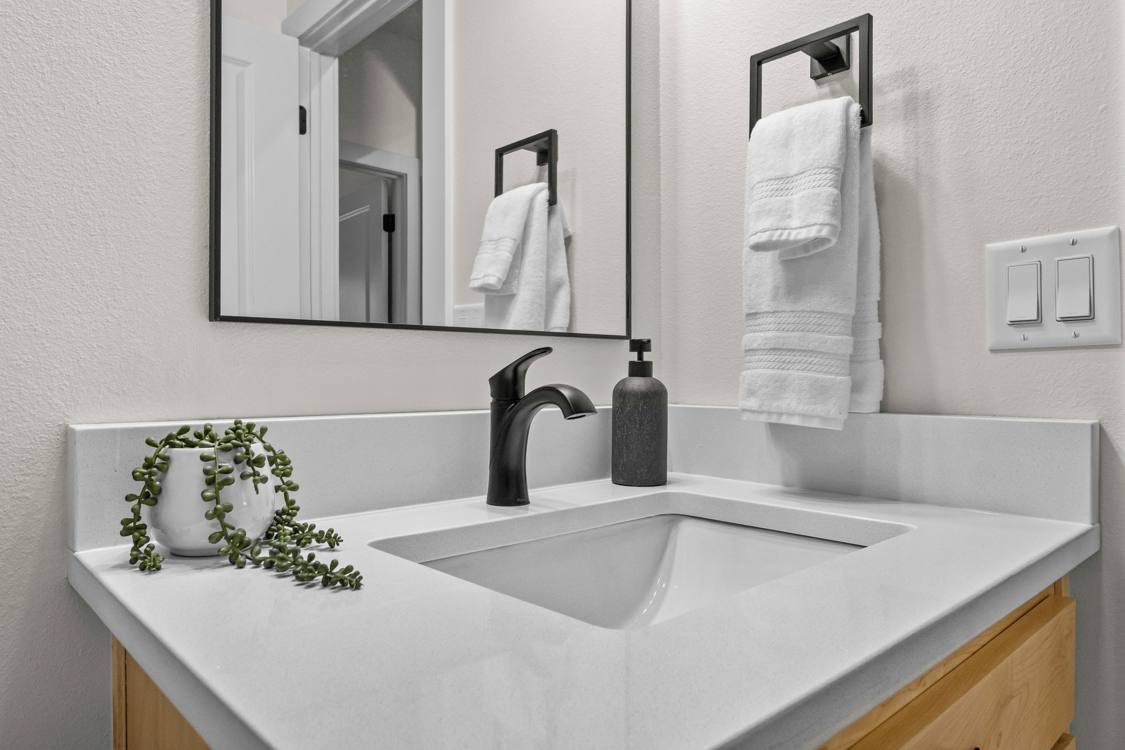 A bathroom with a white sink, black faucet, and a mirror above it.