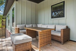 Un espacio de estar al aire libre cubierto, con un sofá, una mesa y dos sillas.