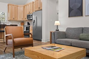 Uma sala de estar moderna com uma poltrona de couro, um sofá cinza e uma mesa de centro de madeira.