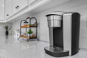 A modern kitchen with a coffee machine, a shelf with a plant, and a white cabinet. - 3-bedroom house in charming Bella Vista with AC for relaxing stays (Bella Vista)