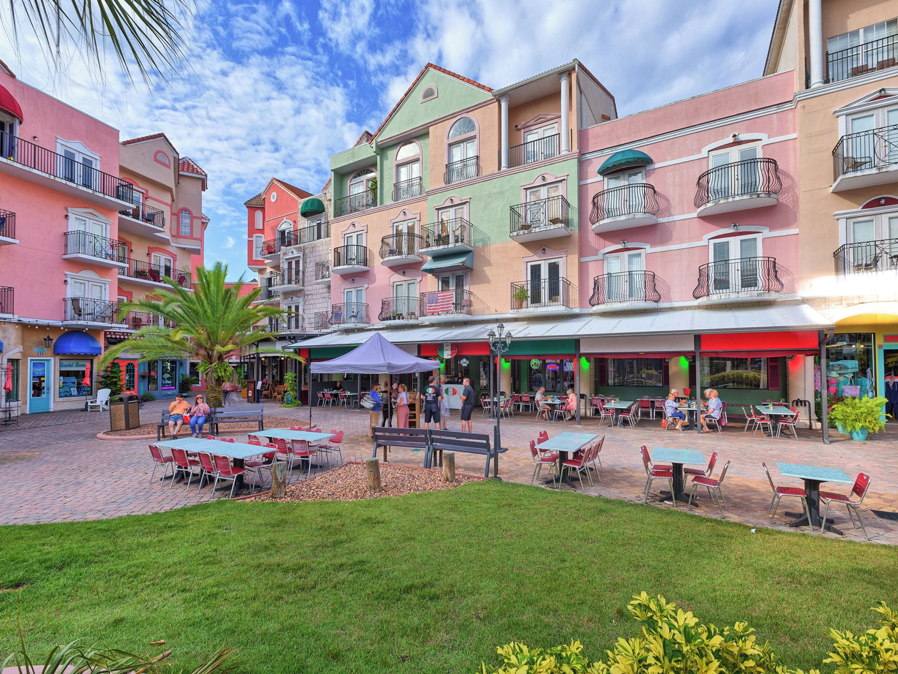 Un patio con asientos al aire libre, rodeado de edificios coloridos con balcones.