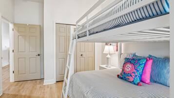Una cama litera con escalera, una mesita de noche con lámpara y una almohada colorida.