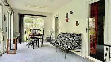 Una habitación con un sofá, una mesa de comedor con sillas, un ventilador de techo y una puerta corrediza de vidrio.