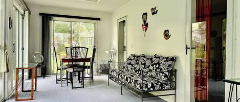 A room with a sofa, a dining table with chairs, a ceiling fan, and a sliding glass door.