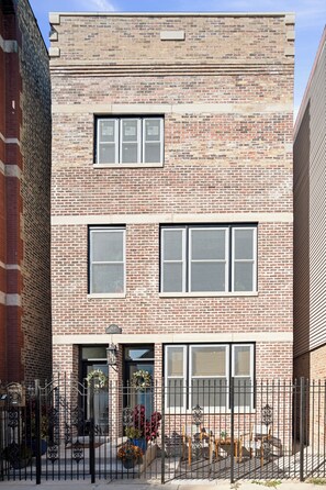 A two-story brick building with a flat roof, large windows, and a metal fence with potted plants. - A peaceful Chicago retreat offering the perfect balance of neighborhood (Chicago)