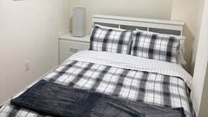A bedroom with a bed, a bedside table, a speaker, and a framed picture on the wall. - Stylish & Newly Built 2 Bedroom Apartment in Milton (Milton)