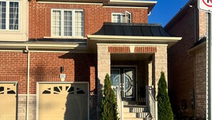A two-story brick house with a garage, a covered front porch, and a driveway. - Stylish & Newly Built 2 Bedroom Apartment in Milton (Milton)