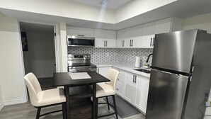 A modern kitchen with a dining table, chairs, a refrigerator, and built-in appliances. - Stylish & Newly Built 2 Bedroom Apartment in Milton (Milton)