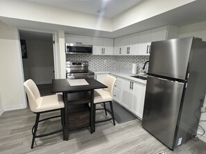 Een moderne keuken met een eettafel, stoelen, een koelkast en ingebouwde apparatuur.