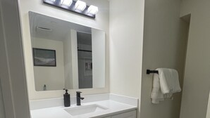 A bathroom with a white sink, a mirror, and a black bath mat. - Stylish & Newly Built 2 Bedroom Apartment in Milton (Milton)