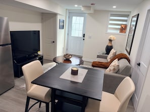 A modern living room with a dining table, chairs, a TV, and a sofa. - Stylish & Newly Built 2 Bedroom Apartment in Milton (Milton)