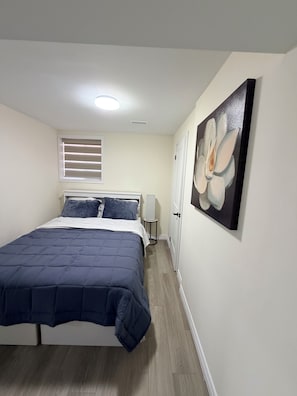 A bedroom with a bed, a window with blinds, a wall-mounted painting, and a bedside lamp. - Stylish & Newly Built 2 Bedroom Apartment in Milton (Milton)