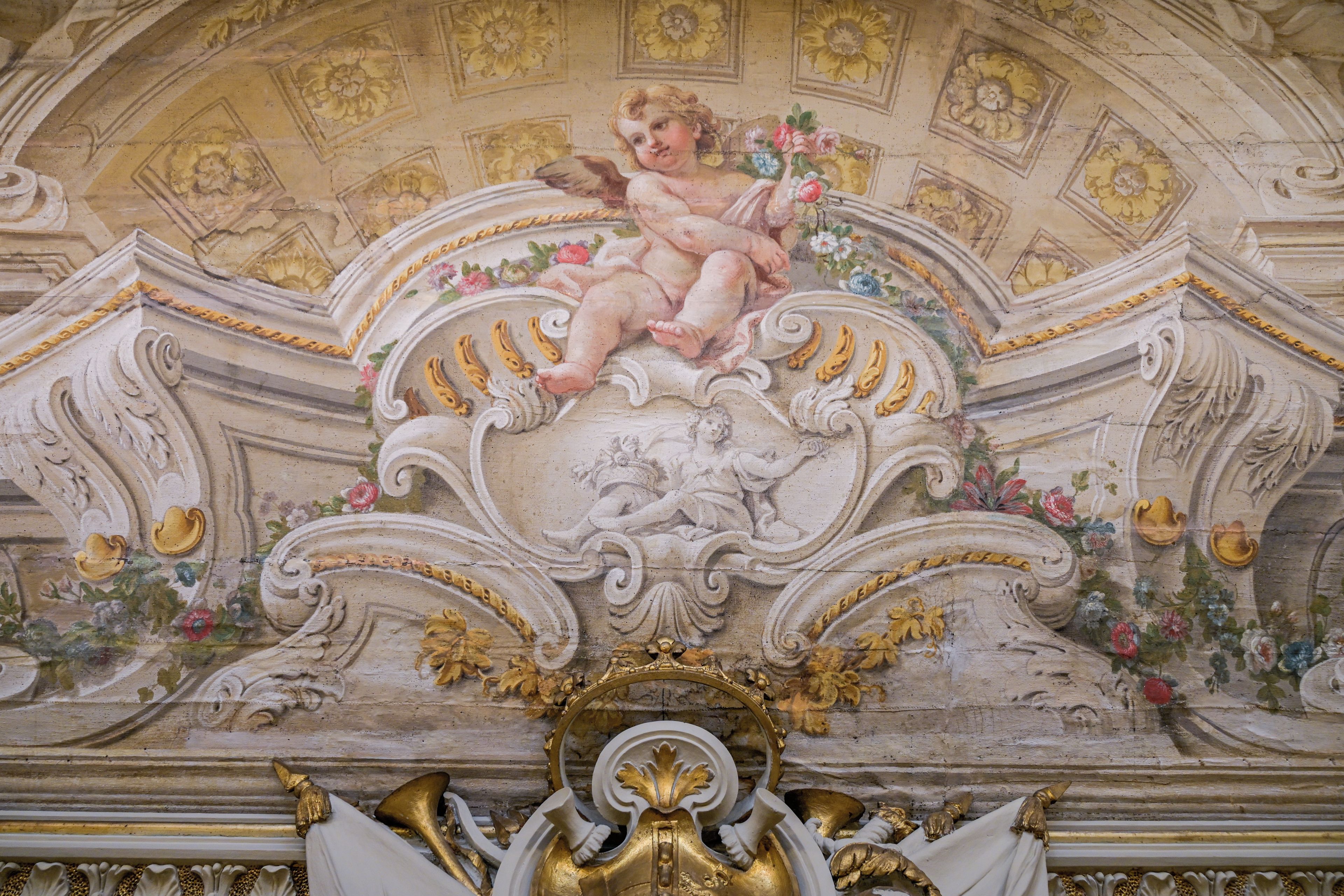 A detailed architectural ceiling with ornate carvings and a central figure.