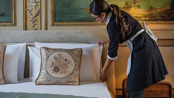Una persona arreglando una cama con muchos almohadones y un cabecero decorativo.