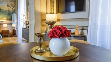 A table with a white vase containing red roses, a candle, and a tray.