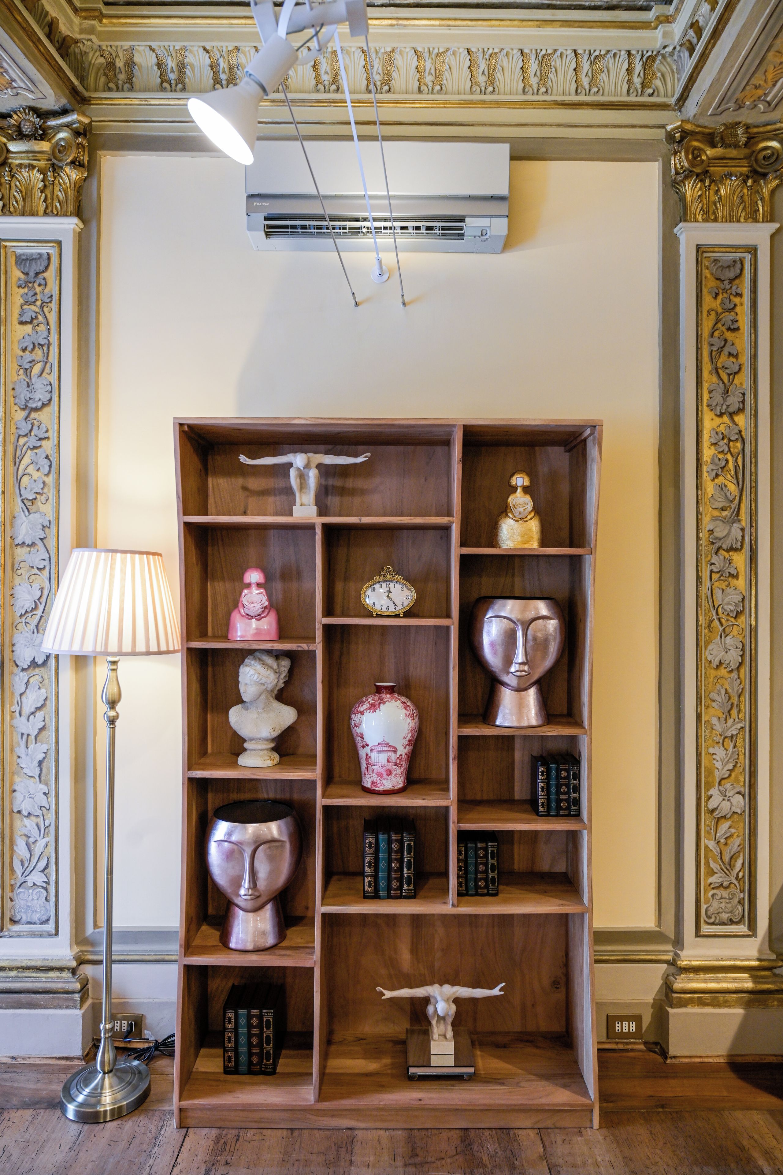 Una habitación con una estantería de madera que contiene varios objetos decorativos y libros.