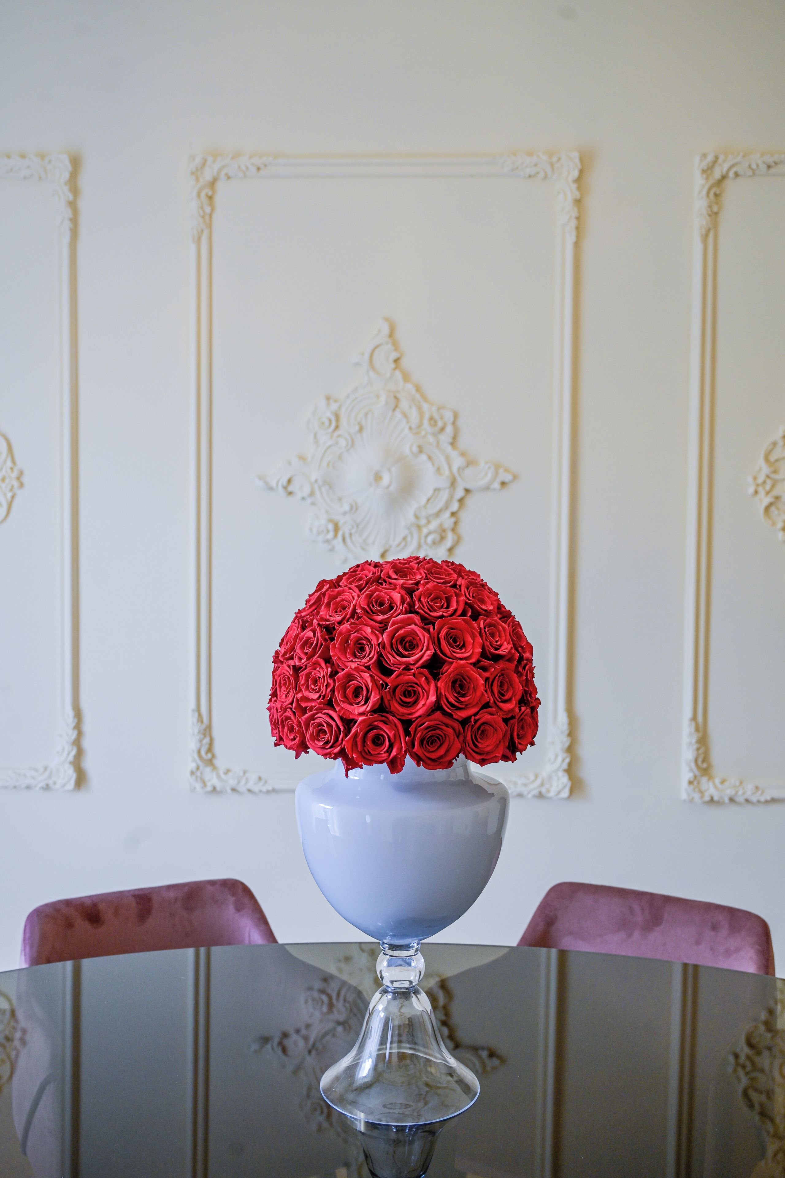 A clear glass vase with a bouquet of red roses on a table.