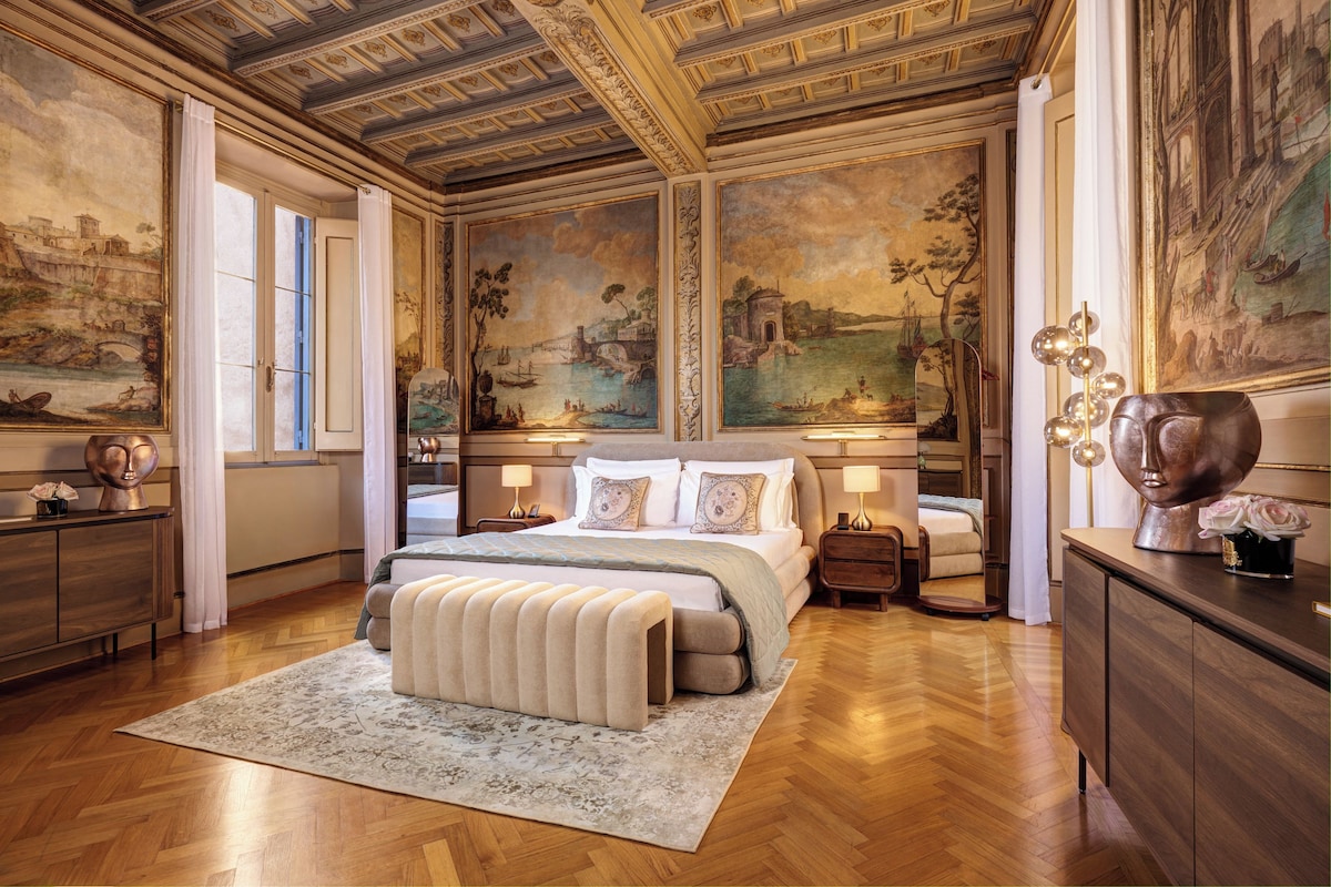 Un dormitorio lujoso con una cama grande, piso de madera y pinturas clásicas en las paredes.