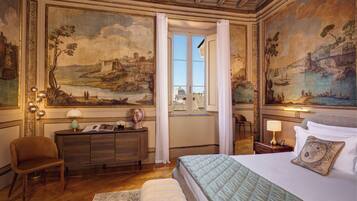 Una lujosa habitación de hotel con una cama grande, un escritorio y vistas de un paisaje urbano a través de una ventana.