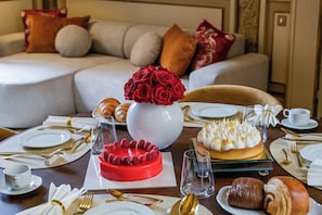 A dining table set with plates, cutlery, glasses, and a variety of desserts including a red cake and a meringue-topped tart. - Palazzo Massimo Boutique Piazza Venenzia (Rome)