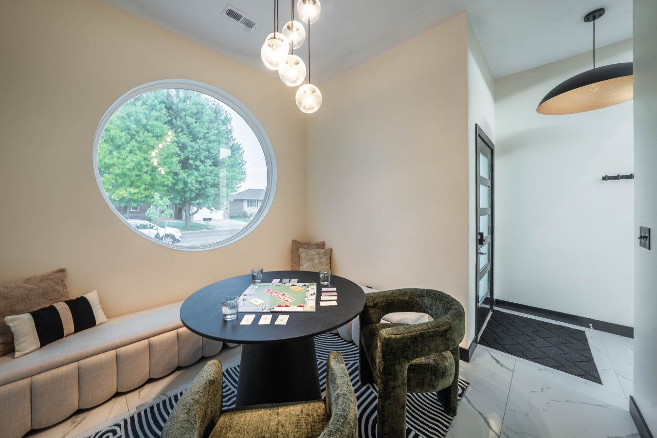Un intérieur moderne avec une table ronde, un canapé et une vue dégagée sur l’extérieur grâce à une grande fenêtre.