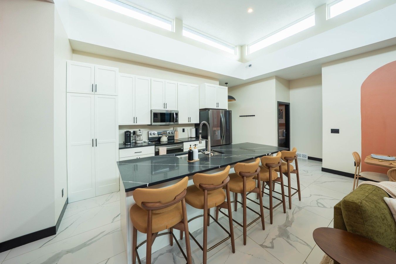 A modern kitchen with white cabinets, a black countertop, and a central island with bar stools.
