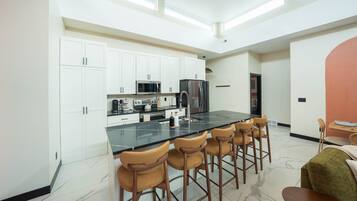 A modern kitchen with white cabinets, a black countertop, and a central island with bar stools.