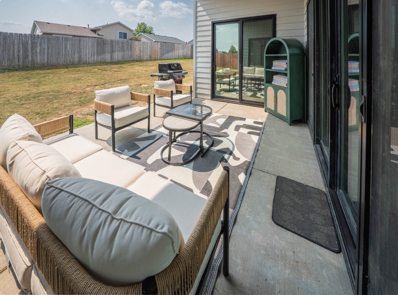 A patio with outdoor furniture, a grill, and a sliding glass door leading to a covered area.