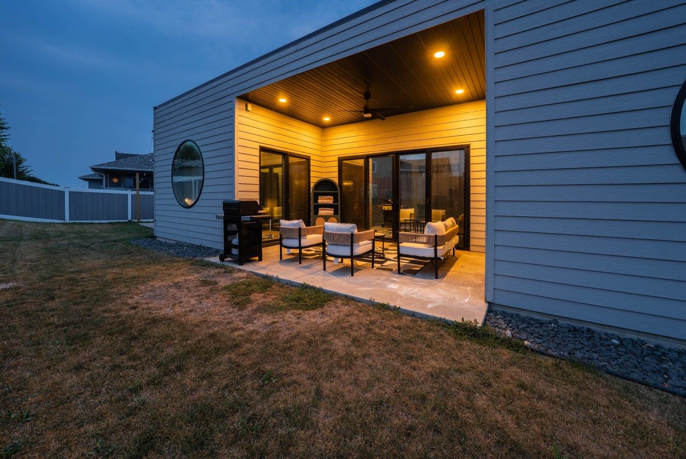 A modern house with a covered patio area featuring outdoor furniture.