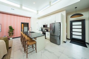 A modern kitchen with a central island, stainless steel appliances, and a bar area with stools.