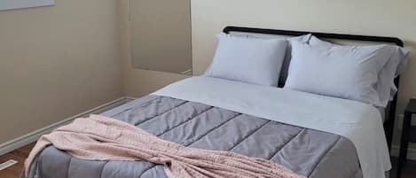 A bedroom with a bed, a nightstand, a window, and a mirror.