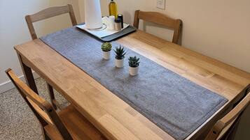 A wooden dining table with a grey placemat, four wooden chairs, and three small potted plants.