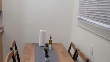 A dining table with a grey placemat, surrounded by wooden chairs. A framed picture hangs on the wall above the table.
