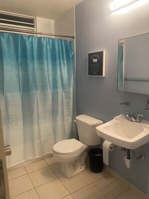 Un baño con inodoro, lavabo y cortina de ducha azul.