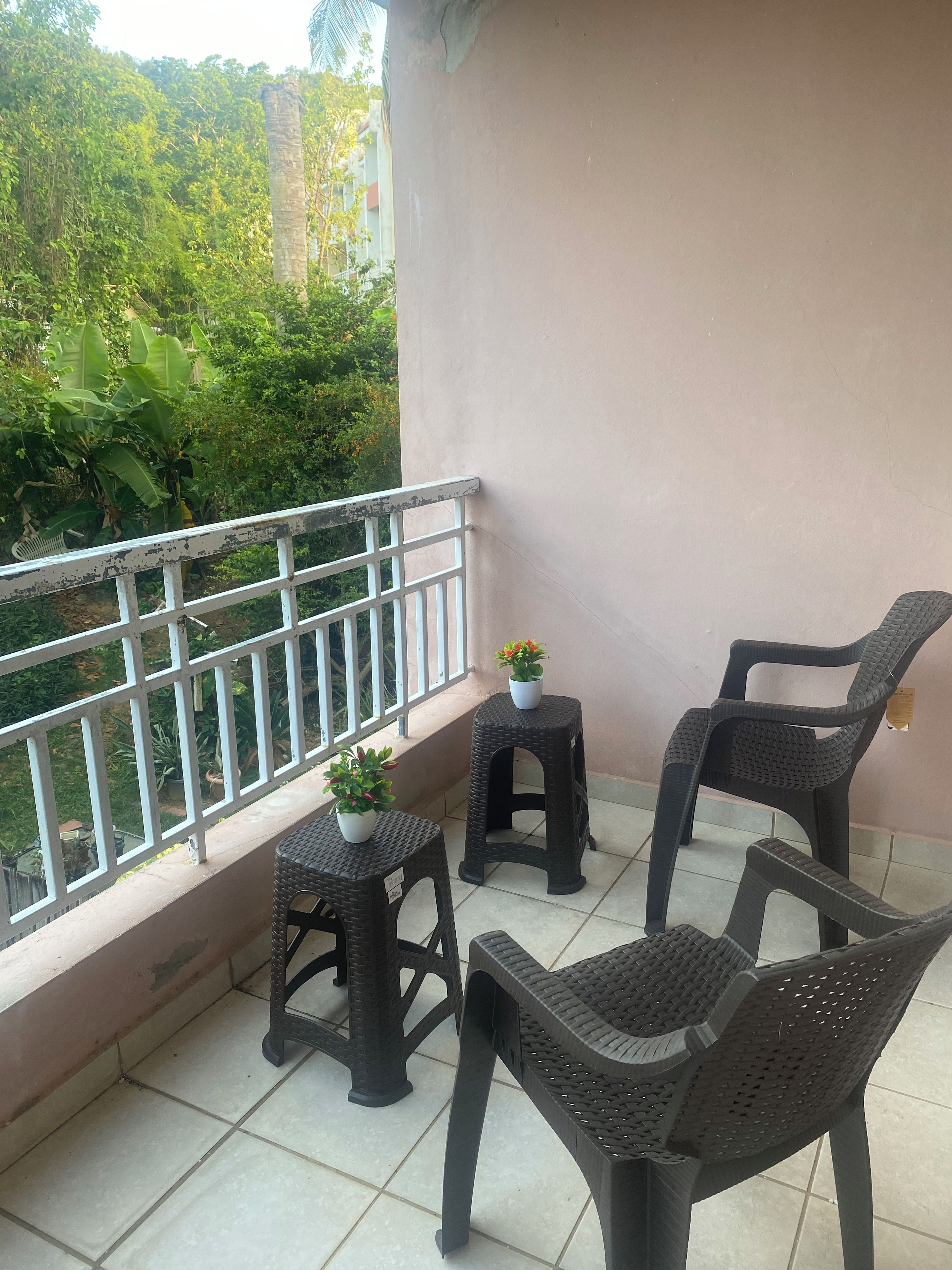 Un balcon avec deux petites tables, deux chaises et des plantes en pot.