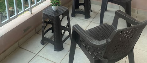 A balcony with two small tables, two chairs, and potted plants.