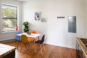 Ein Essbereich mit einem weißen Tisch, bunten Stühlen und einem Blumentopf.