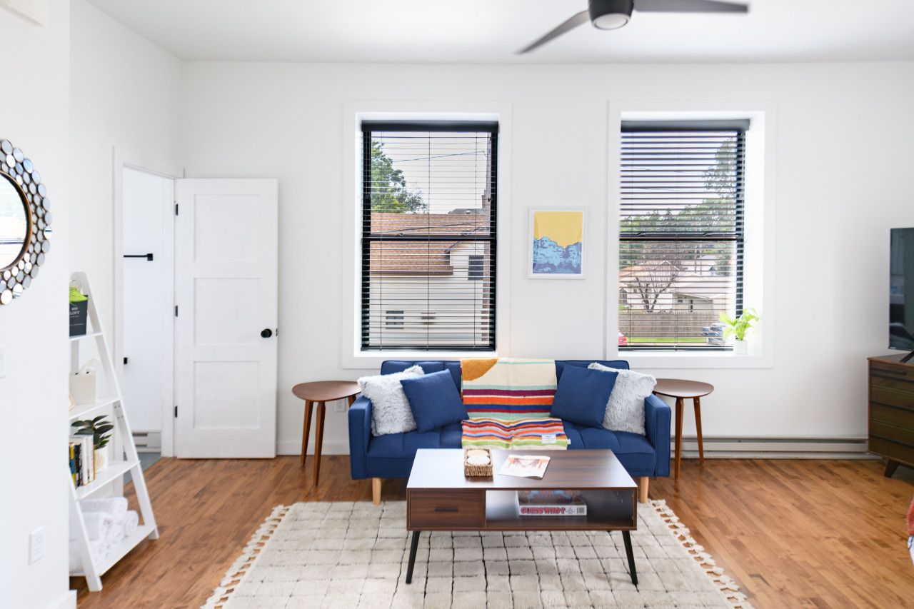 A modern living room with a blue sofa, a coffee table, and a white bookshelf.