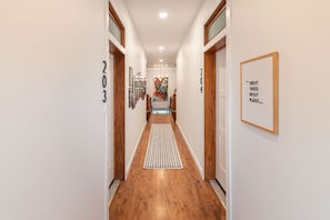 A hallway with wooden flooring, white walls, and a framed inspirational quote. - The Jefferson: Upscale Studio Loft in Downtown SF (Sioux Falls)