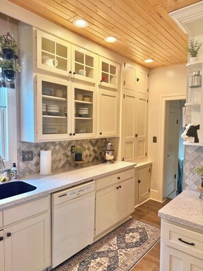 A kitchen with white cabinetry, a granite countertop, and a patterned rug.