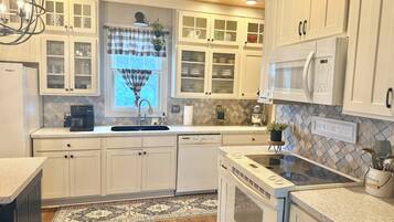 A kitchen with white cabinets, a built-in microwave, a coffee maker, and a dishwasher.