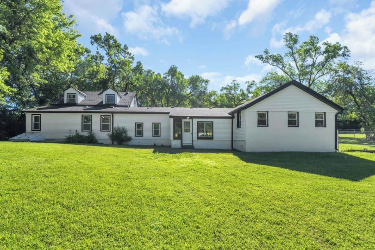 A two-story house with a large front lawn, a garage, and a detached garage.